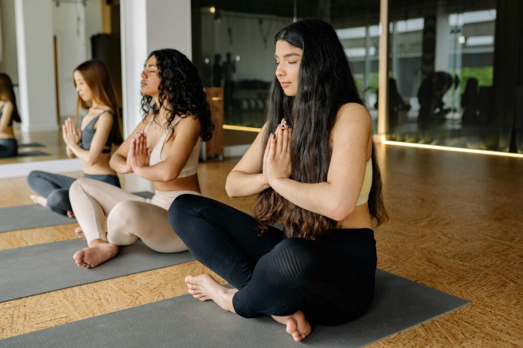 Group of diverse women practicing yoga indoors, focusing on meditation and relaxation.